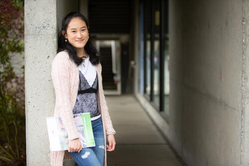 Smiling young woman holding a notebook.