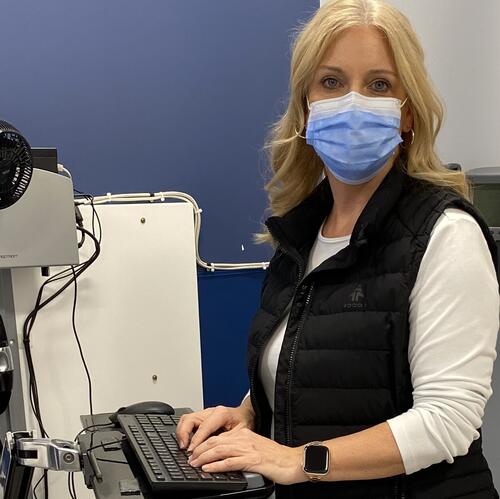 Woman with blonde hair in scrubs working with medical equipment. 