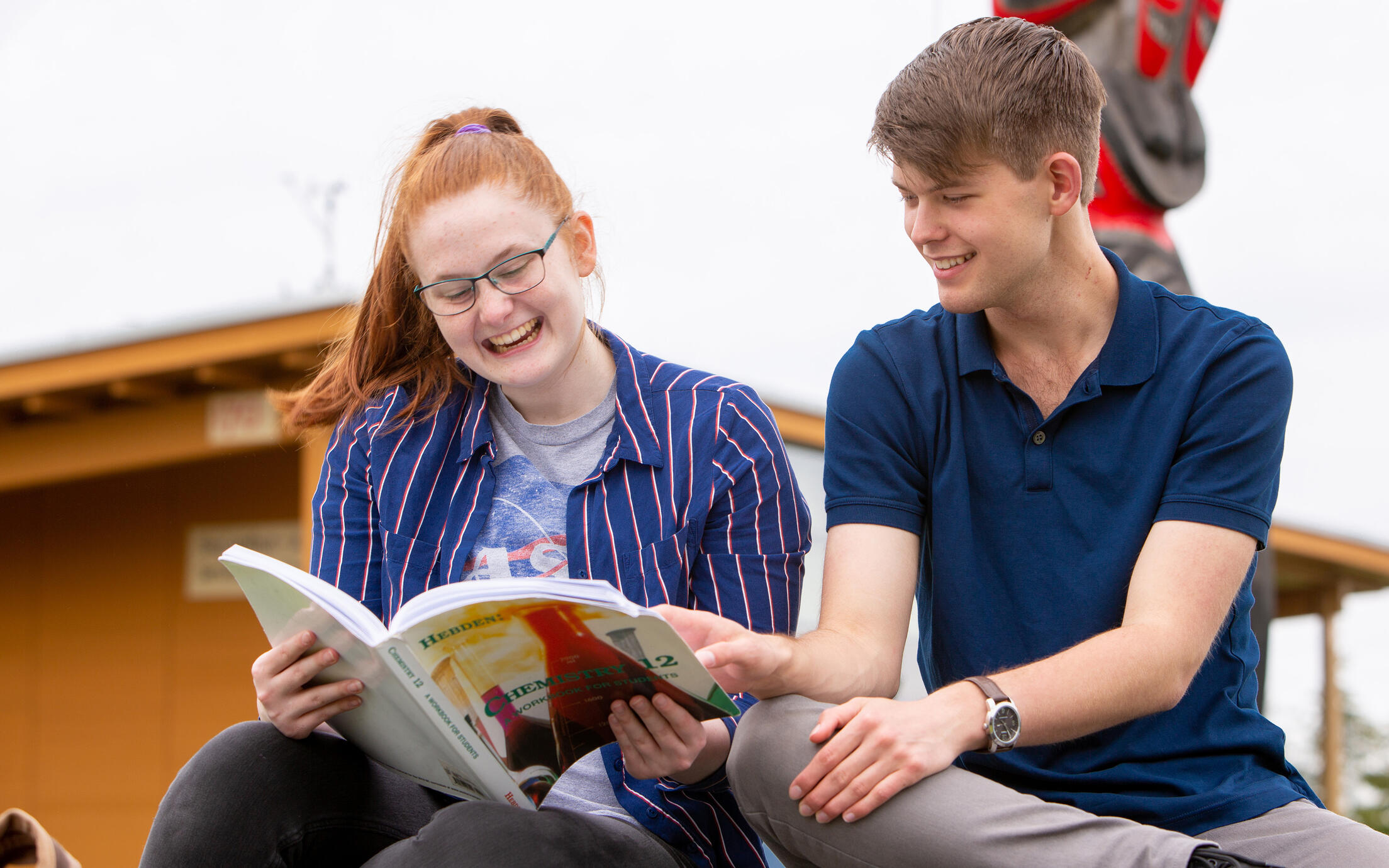Two teens reading a textbook together