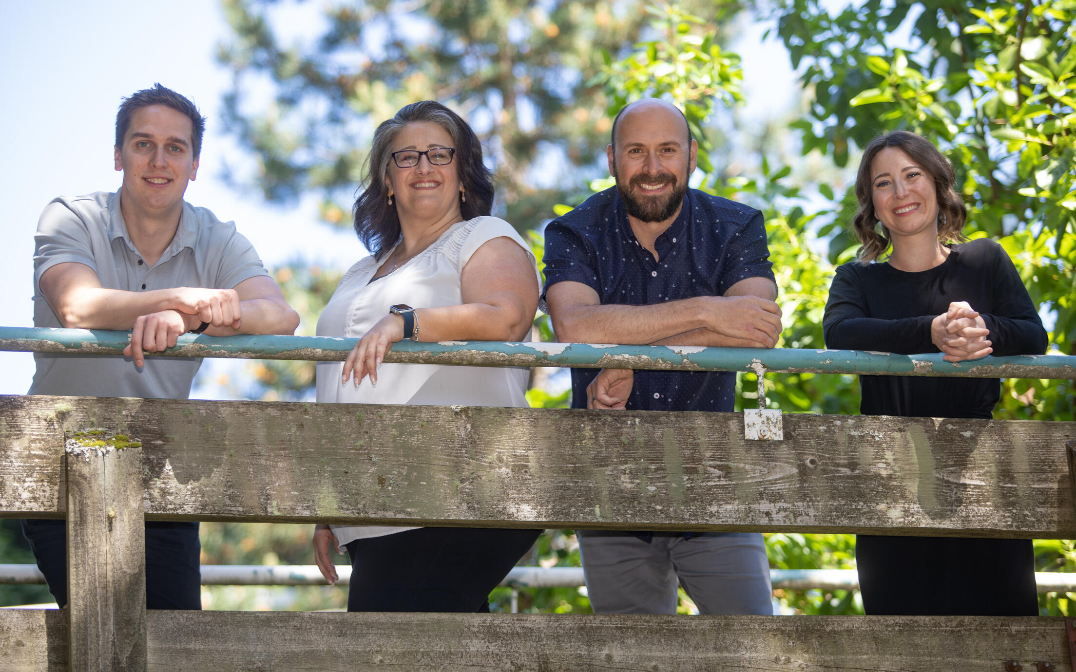 four happy people standing at a railing. 