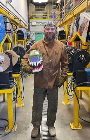 Smiling man in a welding shop.